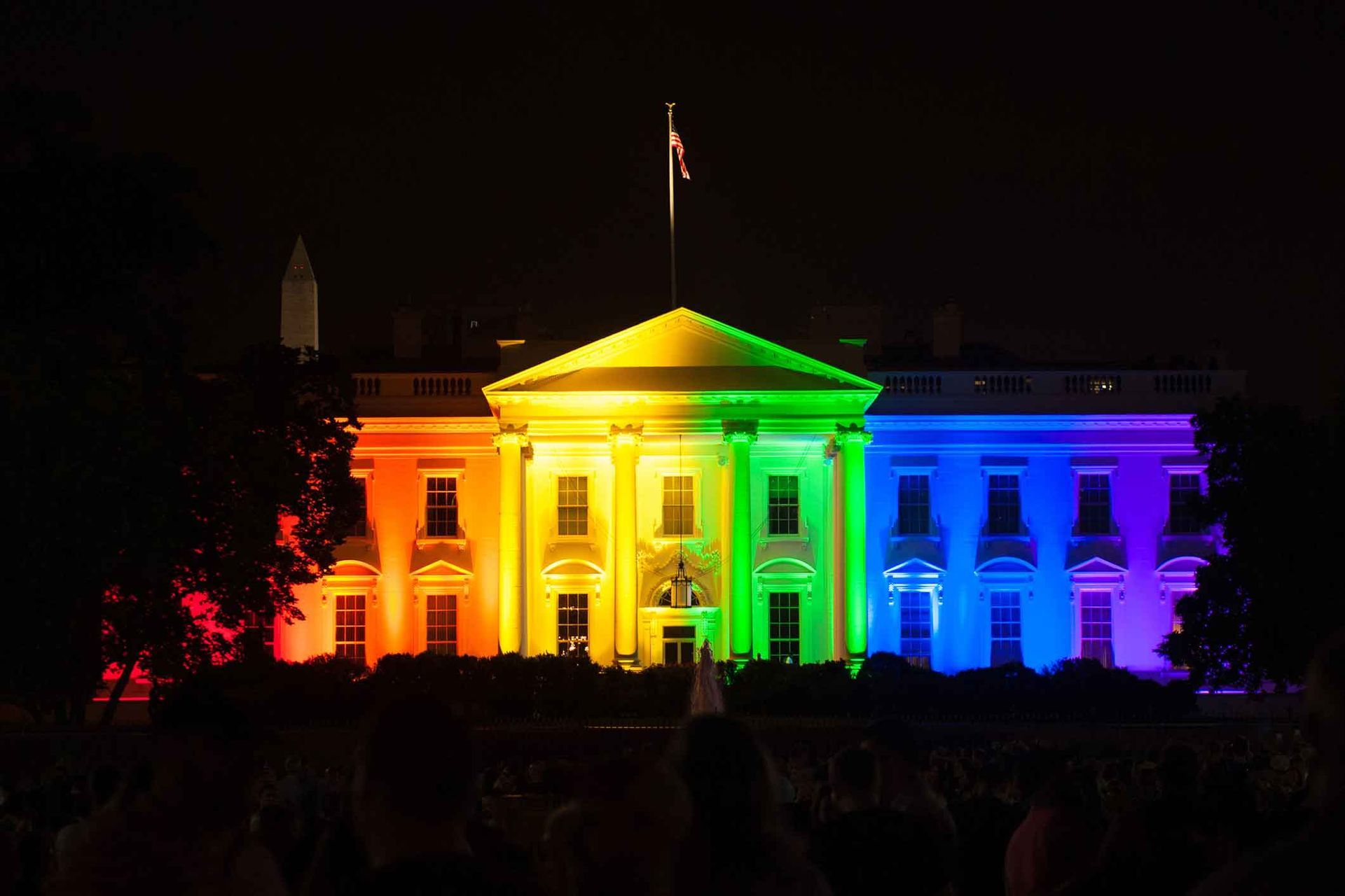 The White House is lit up in rainbow colors at night