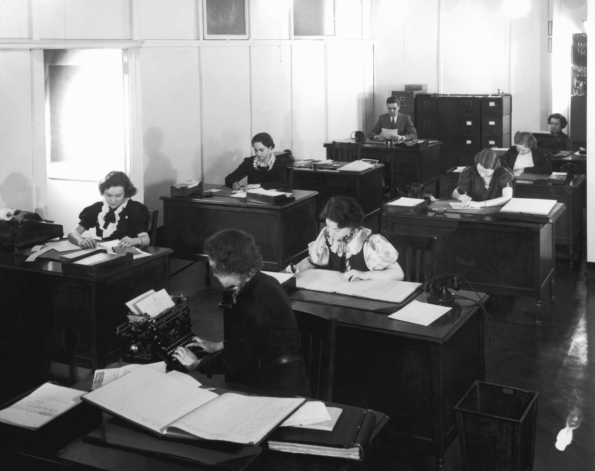 A black and white photo of people working in an office