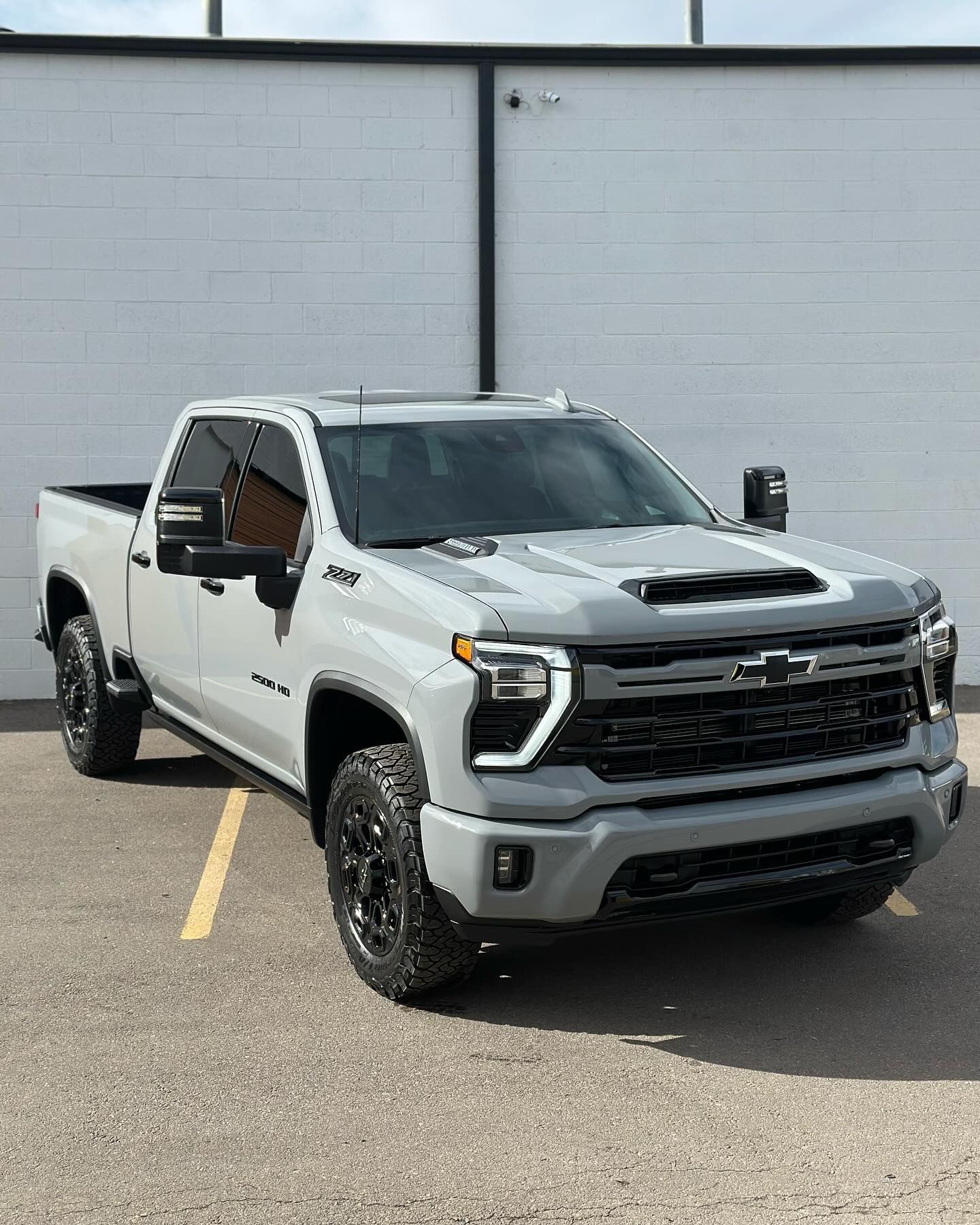A white sports car is parked in a garage next to a red stool.