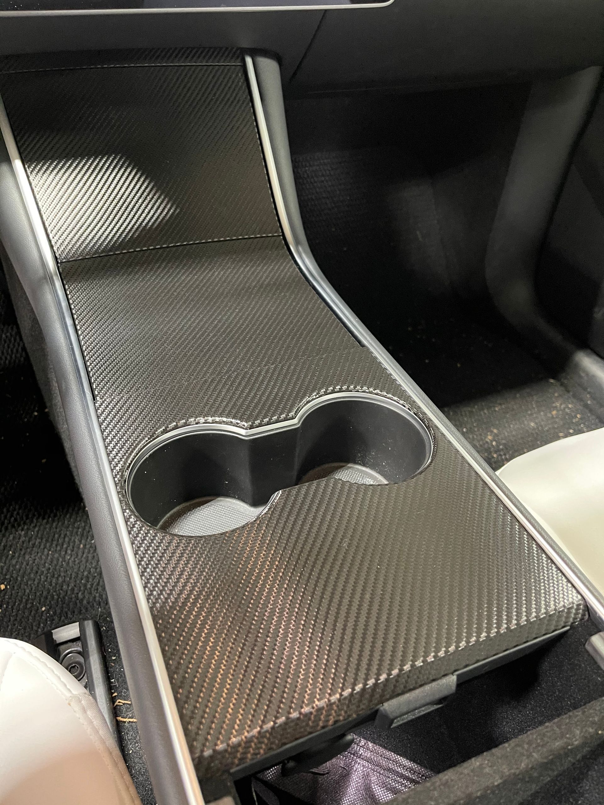 A tesla model 3 center console with a cup holder.