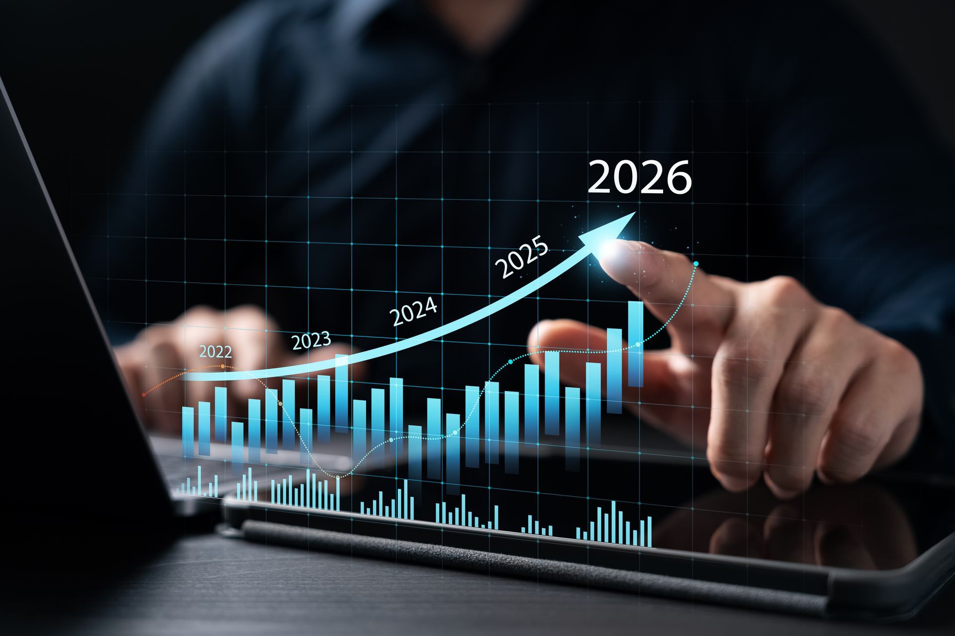 Person pointing at a digital stock chart, with a rising blue line and projected date of 2026.