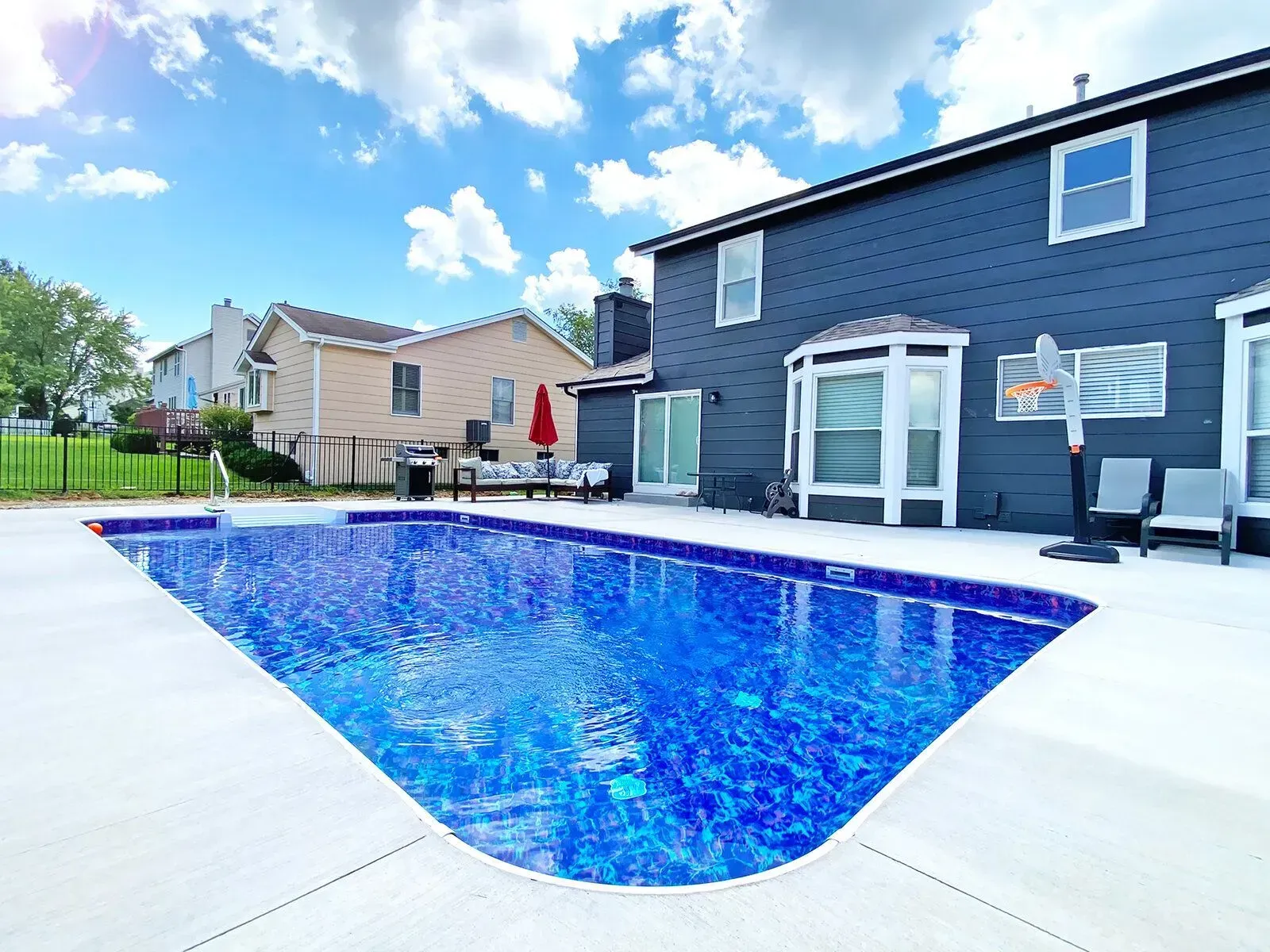 A large swimming pool is in the backyard of a house.