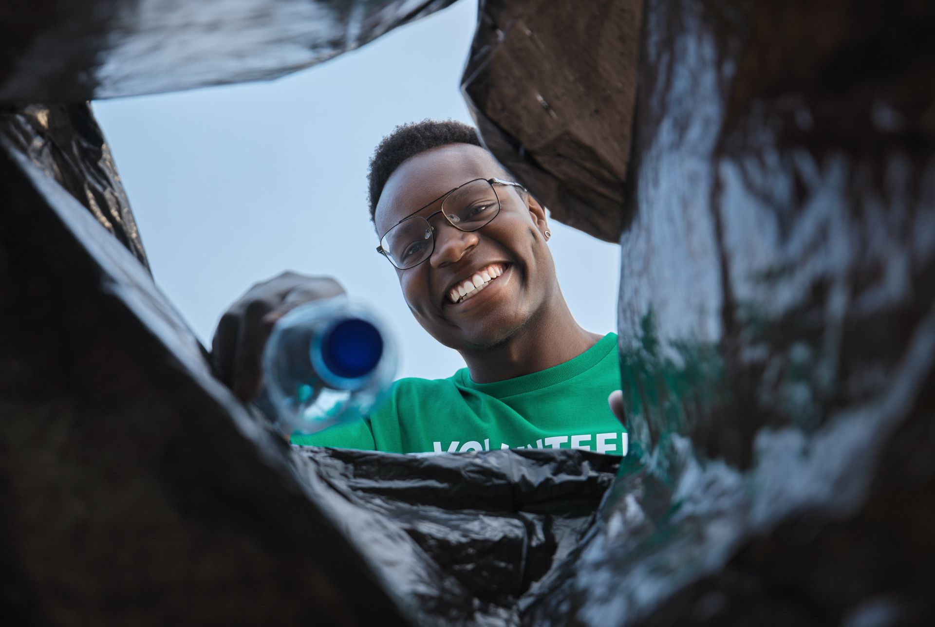 A man is smiling while looking into a trash can.