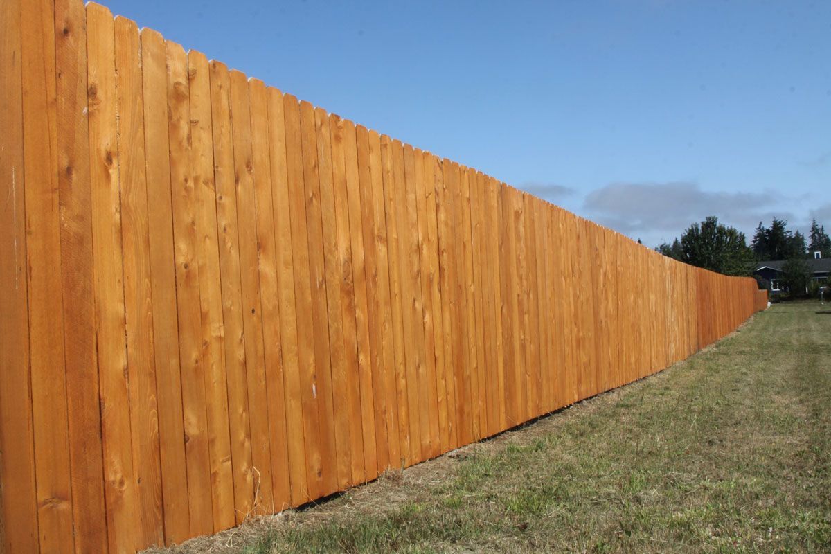 A long wooden fence is sitting in the middle of a grassy field.