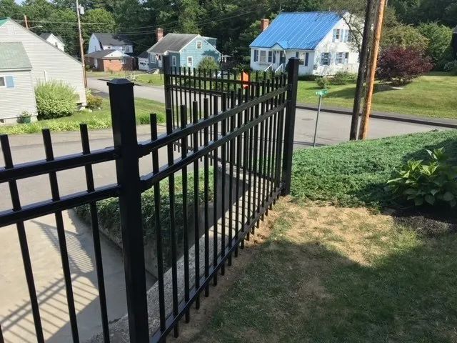A black fence with a blue house in the background