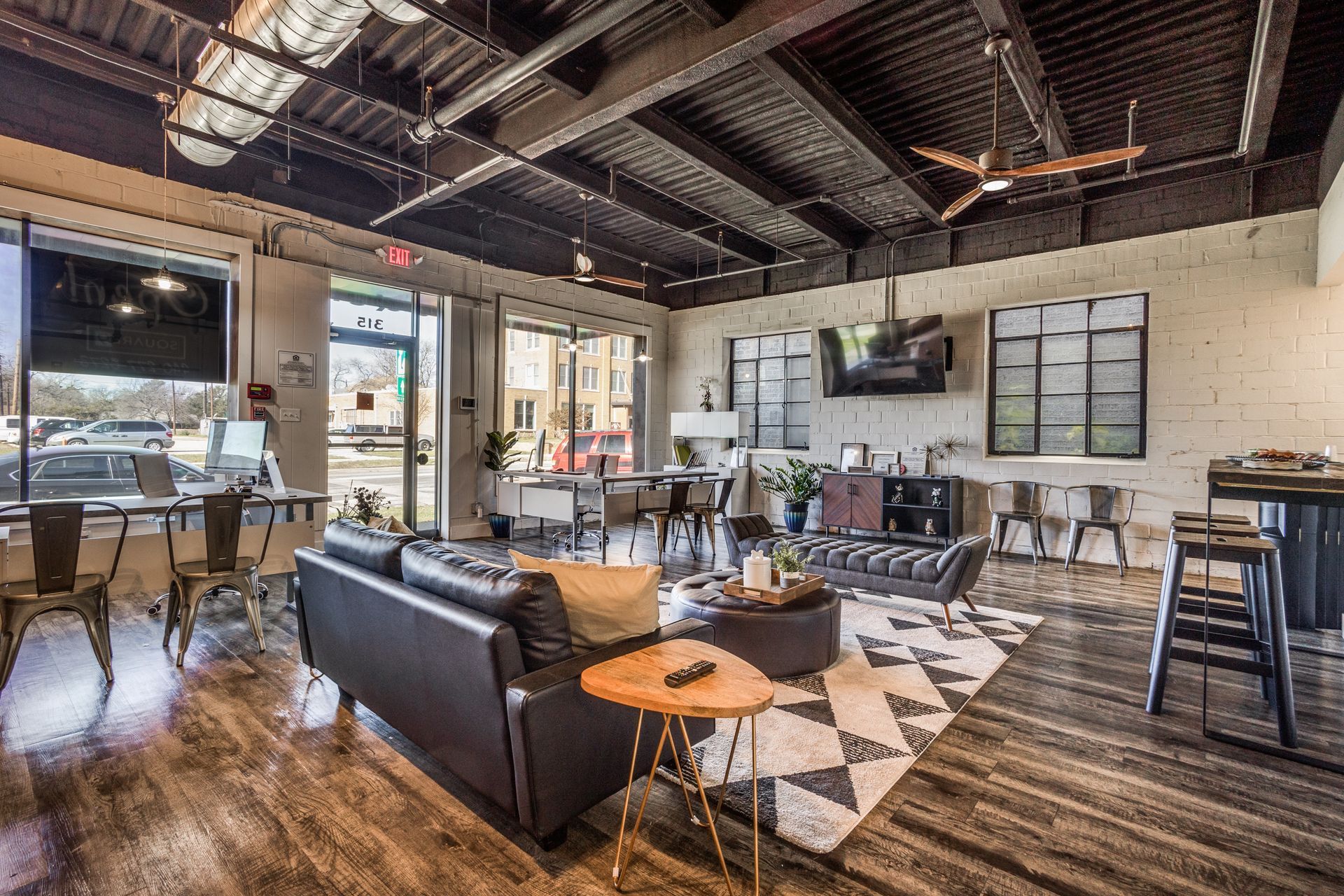 Modern office lounge with leather sofa, geometric rug, and industrial decor.