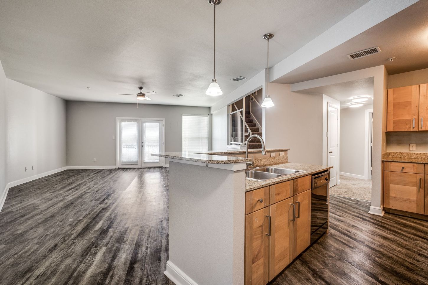 Open-concept kitchen and living area with wood floors, island, and doors to a patio.