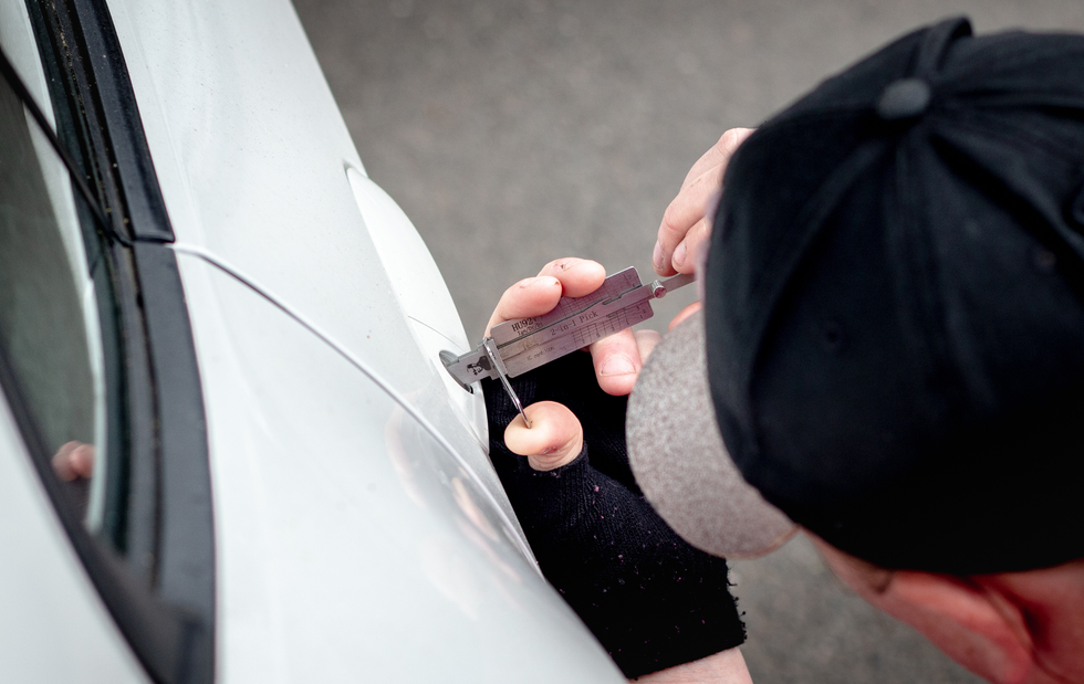 Person using lock pick on a car door.