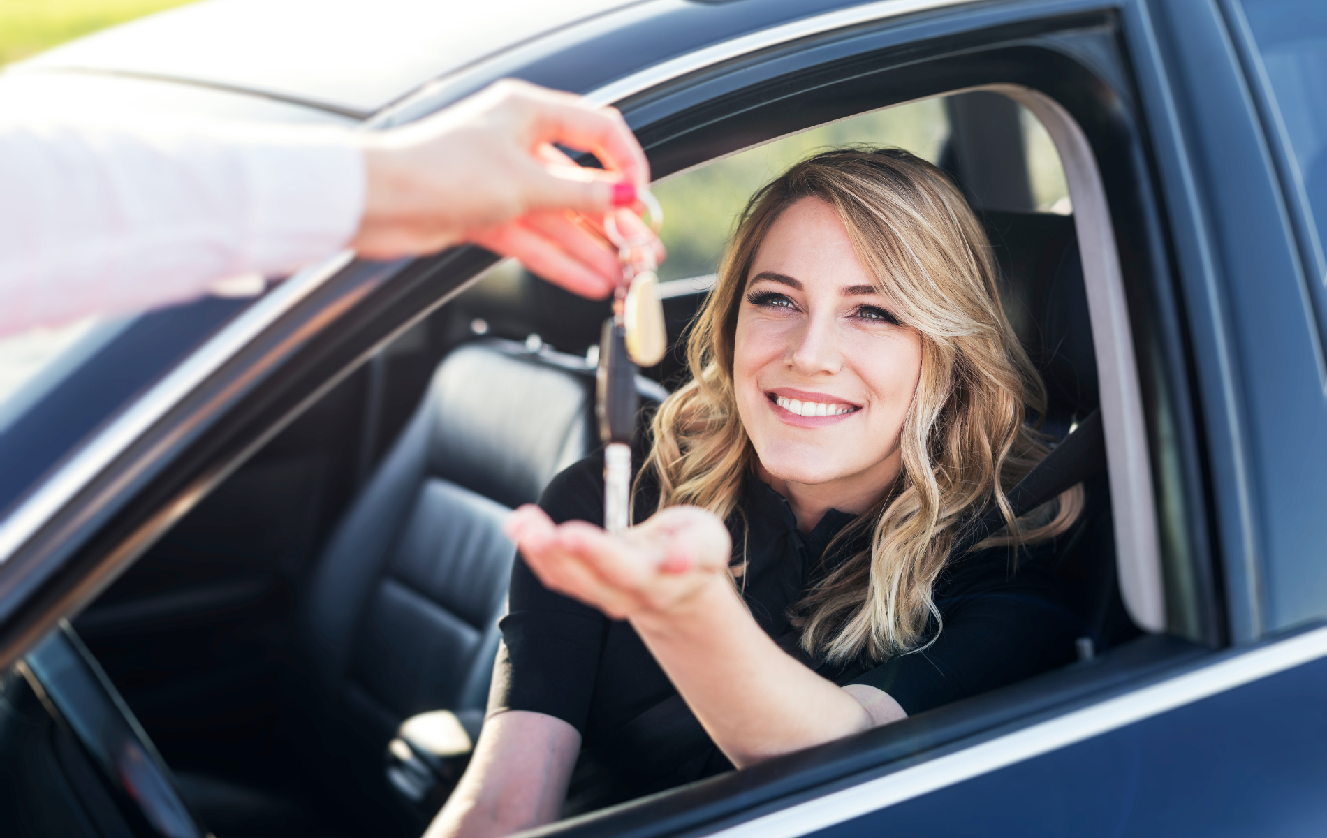 Person in car smiling, receiving car keys.