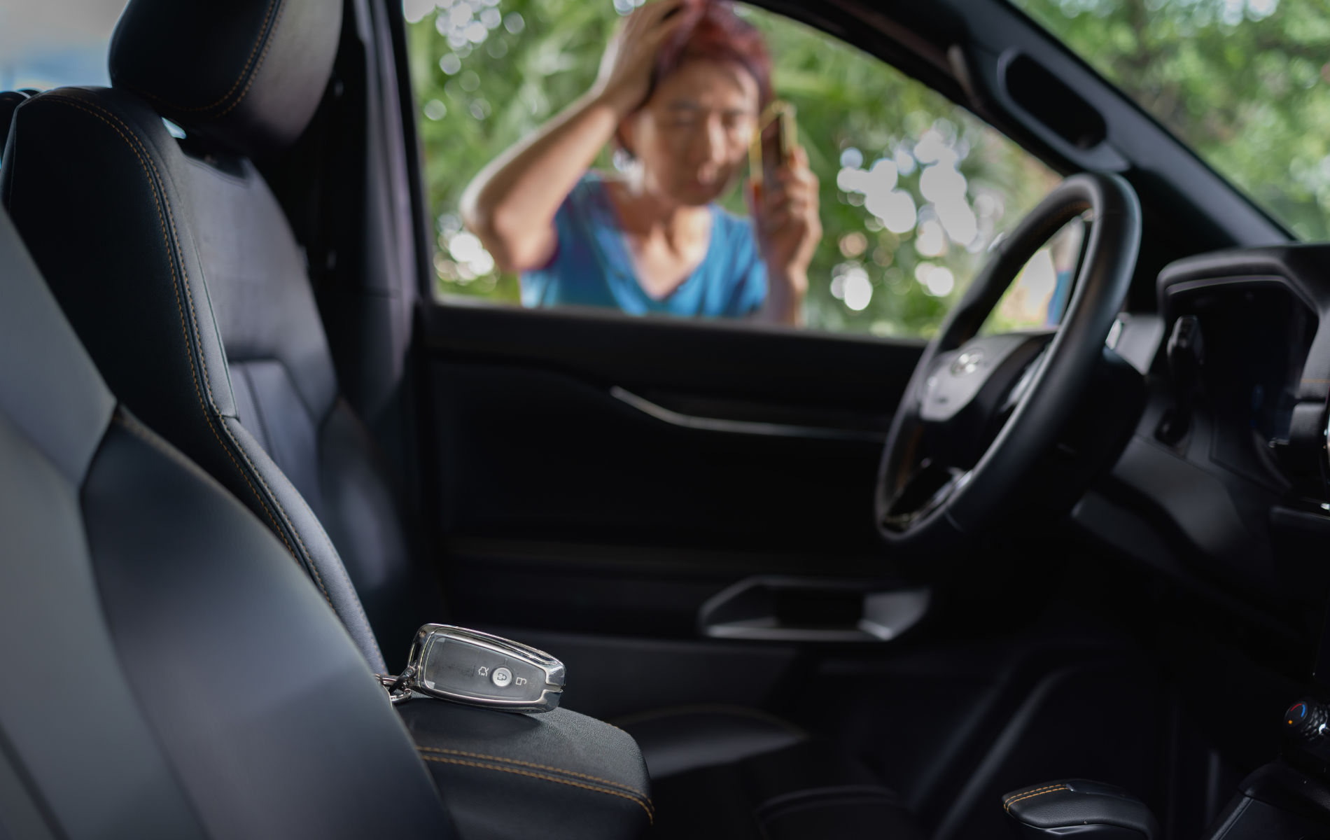 A car interior with keys on the console; a person outside the car looks distressed, holding a phone.