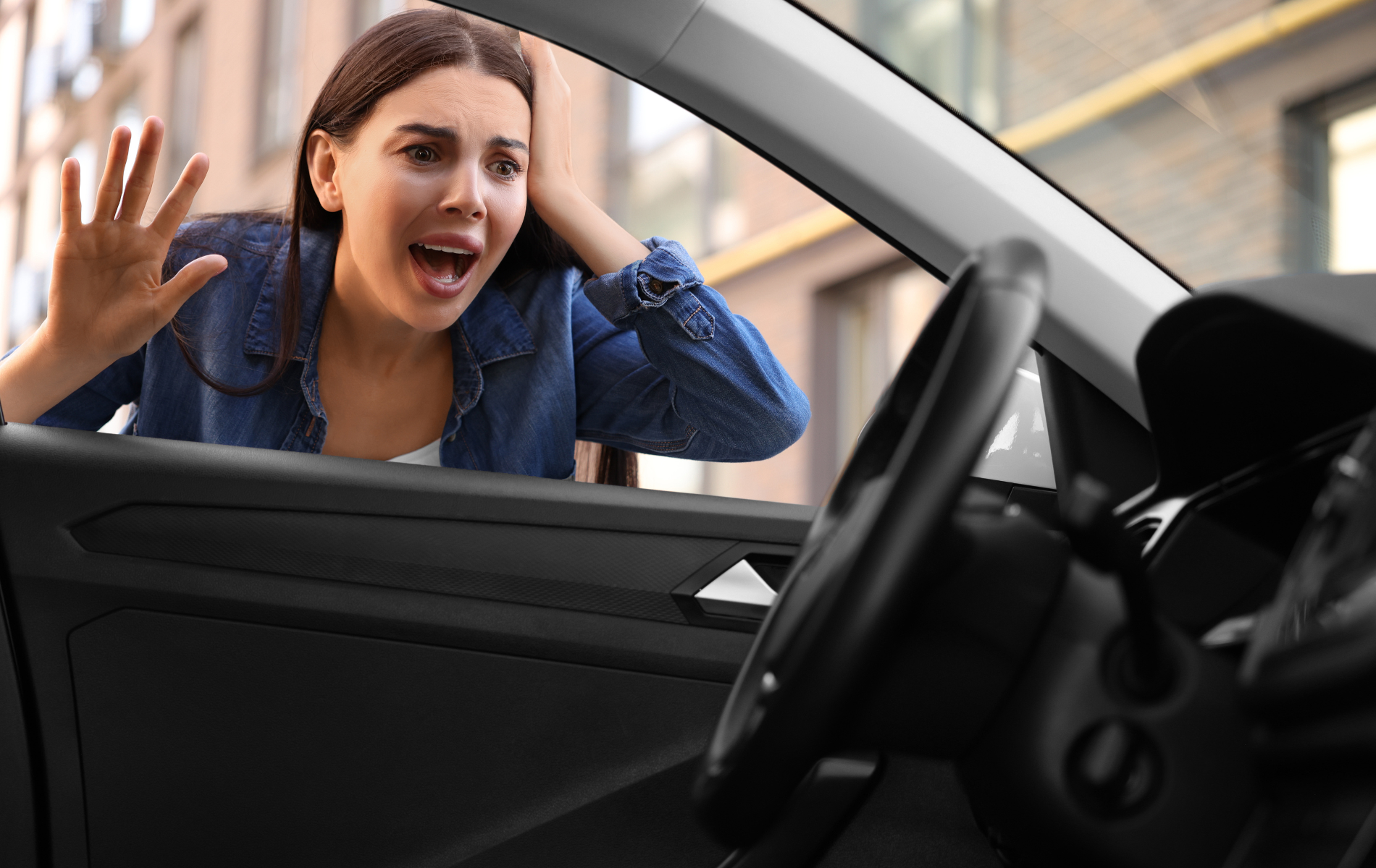 Woman locked out of her car, looking stressed with hand raised near open window, vehicle interior visible.