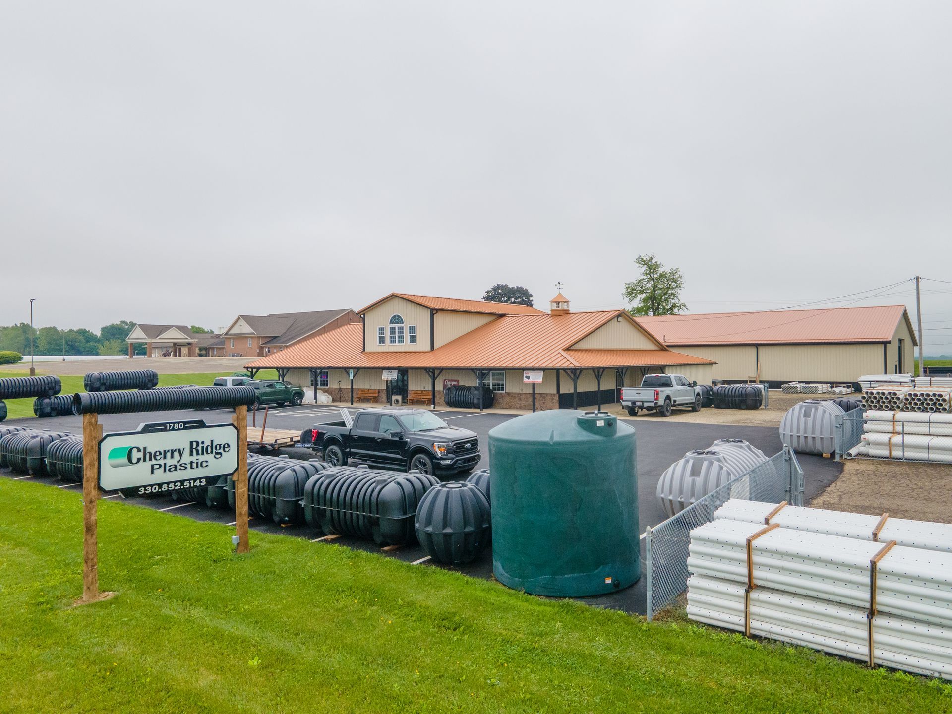Industrial machine cutting green pipe in a workshop; debris scattered.