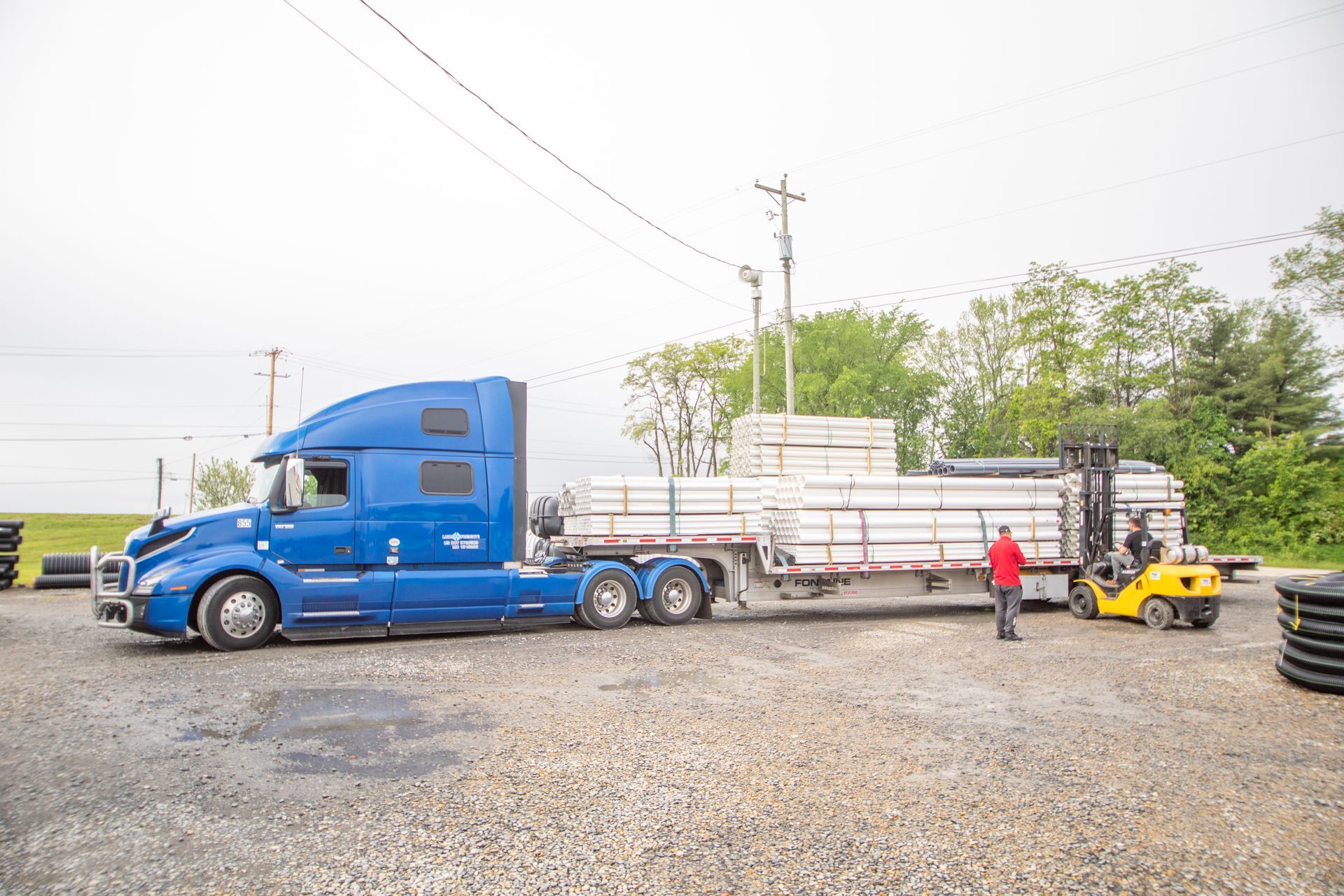 Industrial machine cutting green pipe in a workshop; debris scattered.