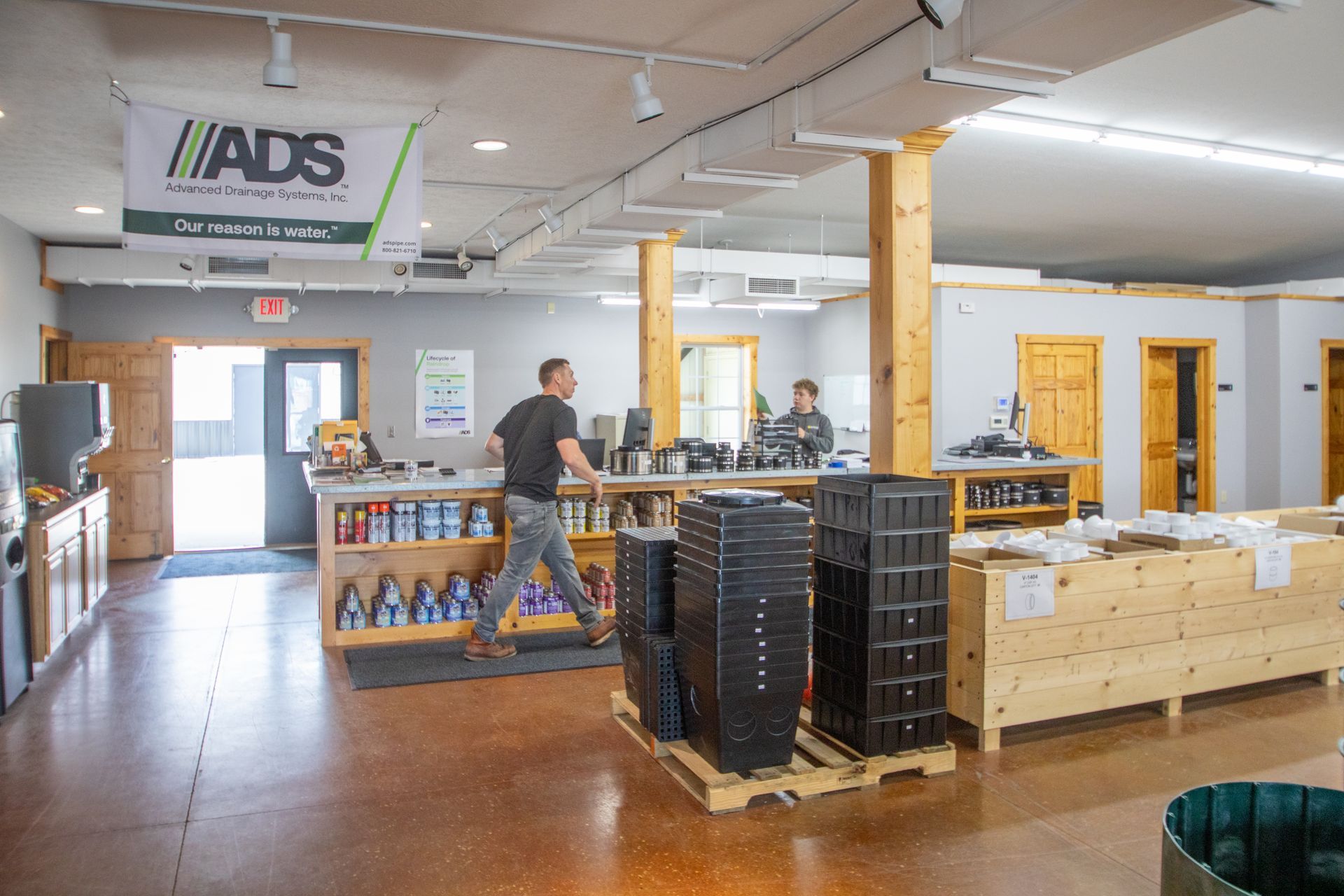 Factory floor with machinery cutting and assembling green PVC pipes.