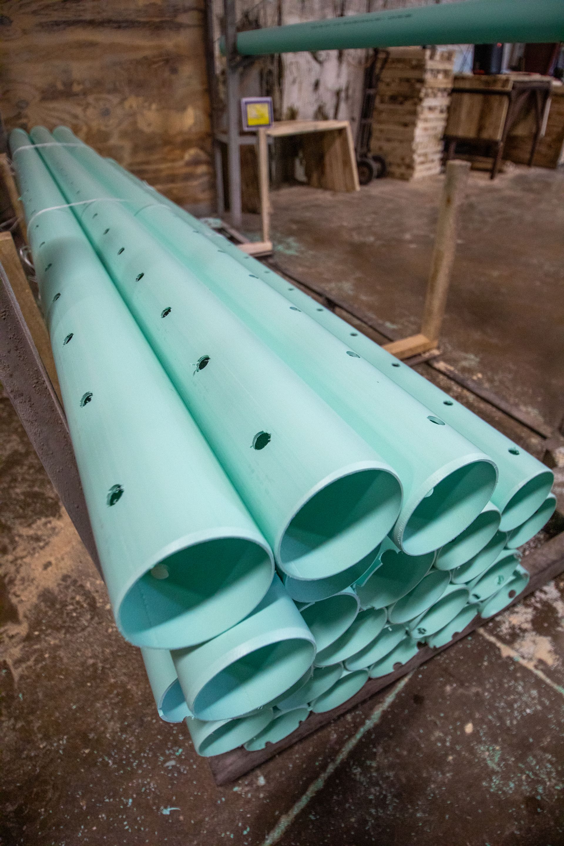 Factory floor with machinery cutting and assembling green PVC pipes.