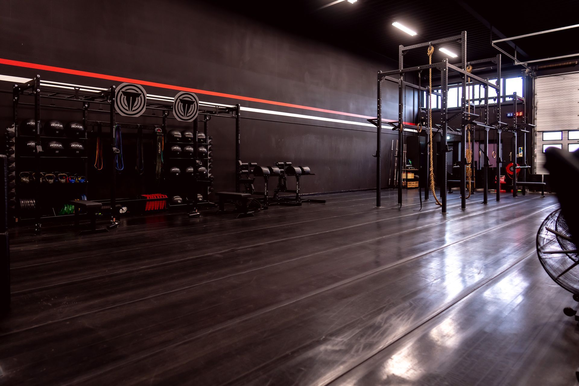 Een sportschool met veel apparatuur en een persoon die in het midden staat.