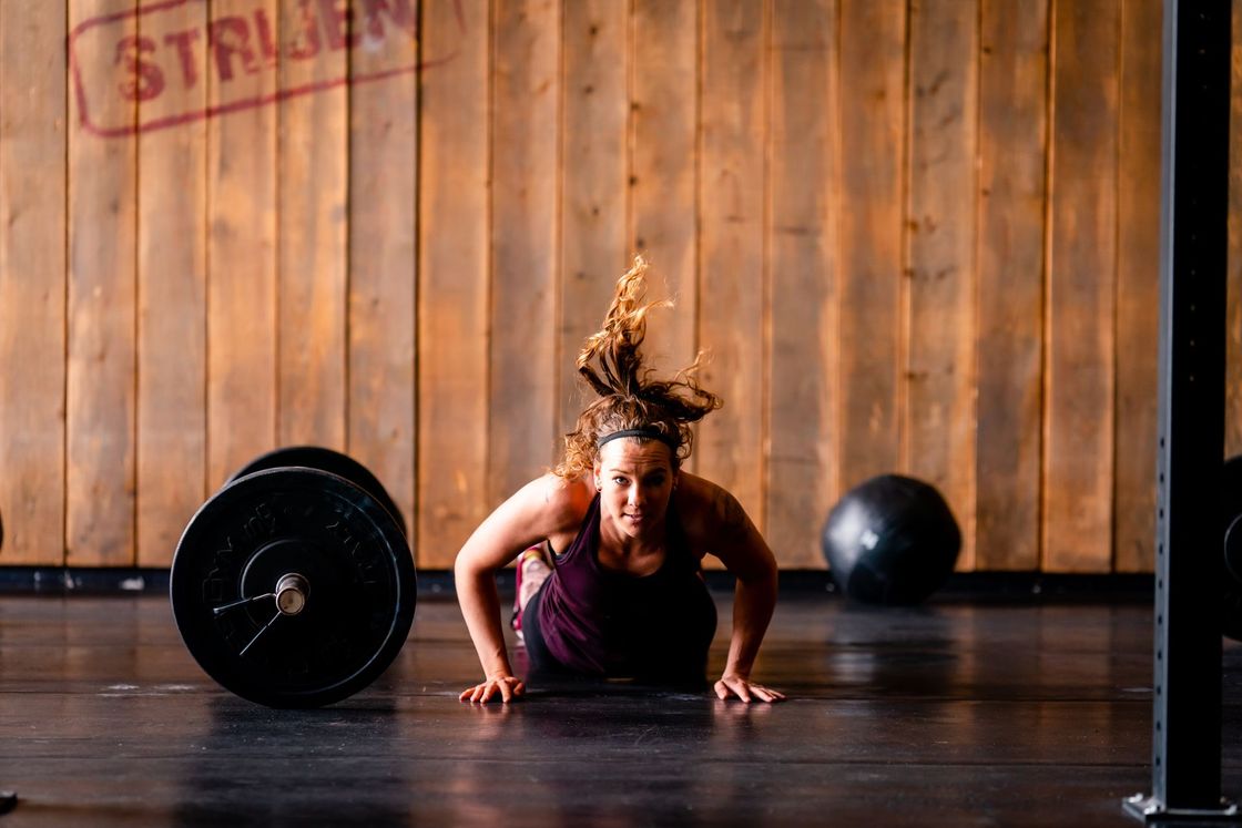 Een vrouw doet push-ups op de vloer in een sportschool.