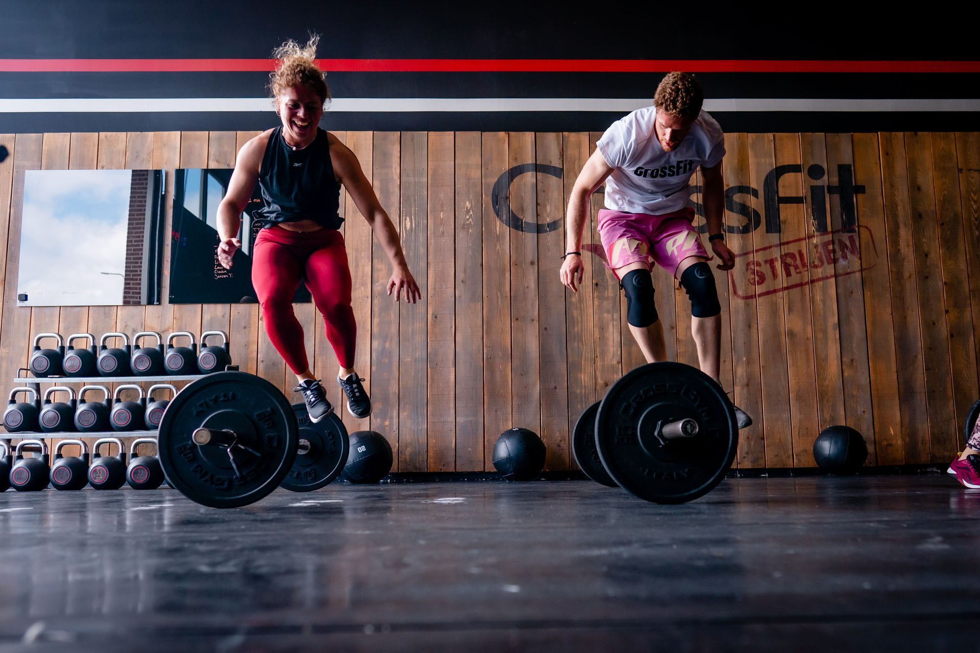 Twee vrouwen springen over halters in een sportschool.