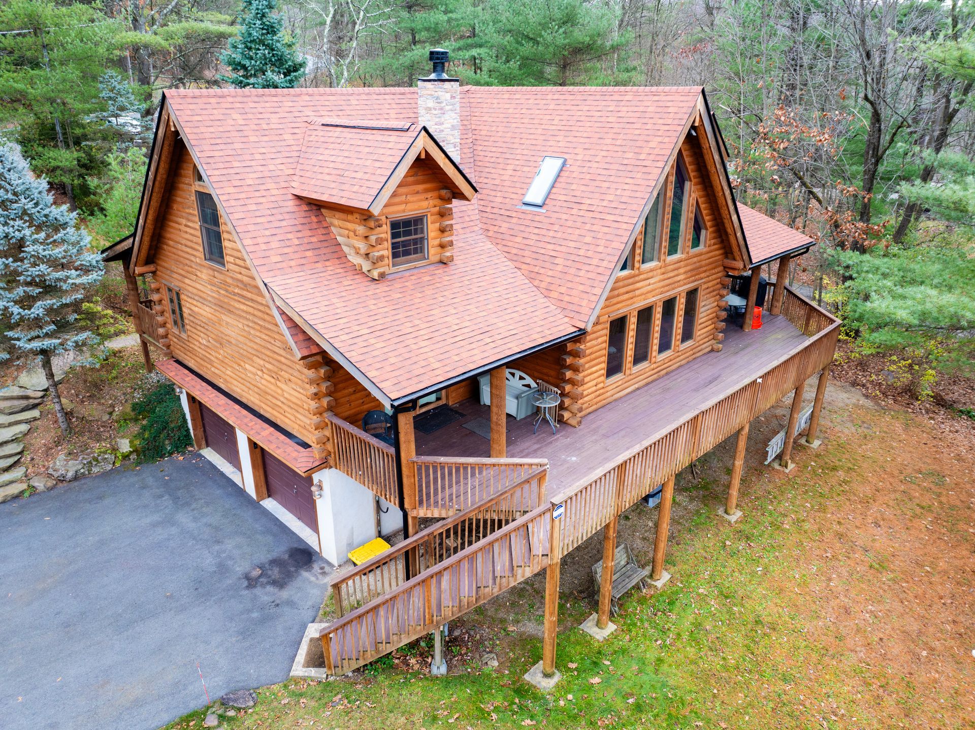 A house with a chimney on the roof is surrounded by trees.