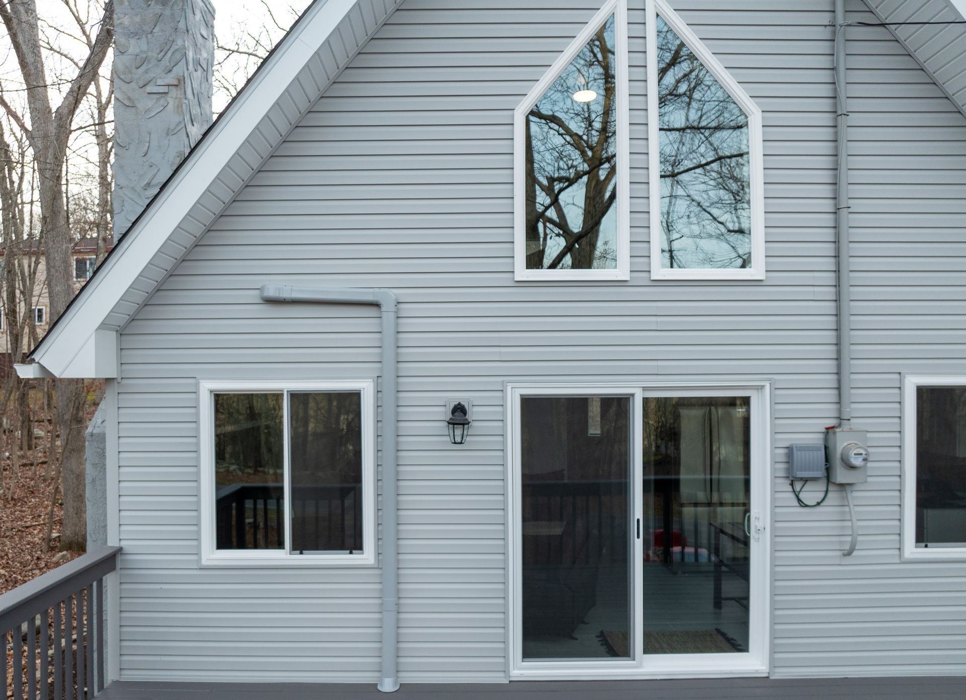 The back of a house with a sliding glass door and a lot of windows.