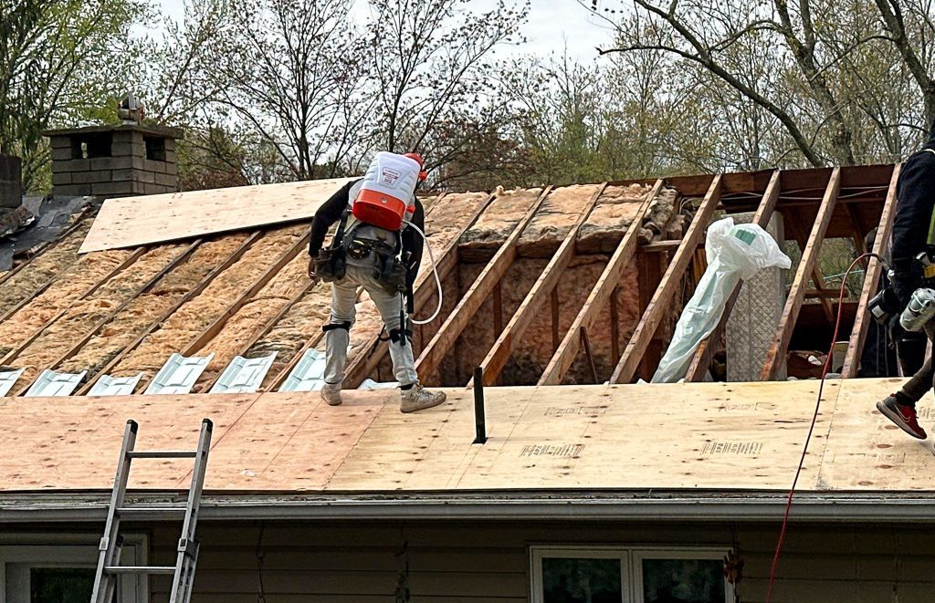 A group of men are working on the roof of a house.