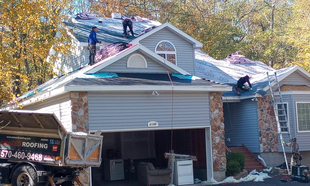 A roofer is working on the roof of a house.