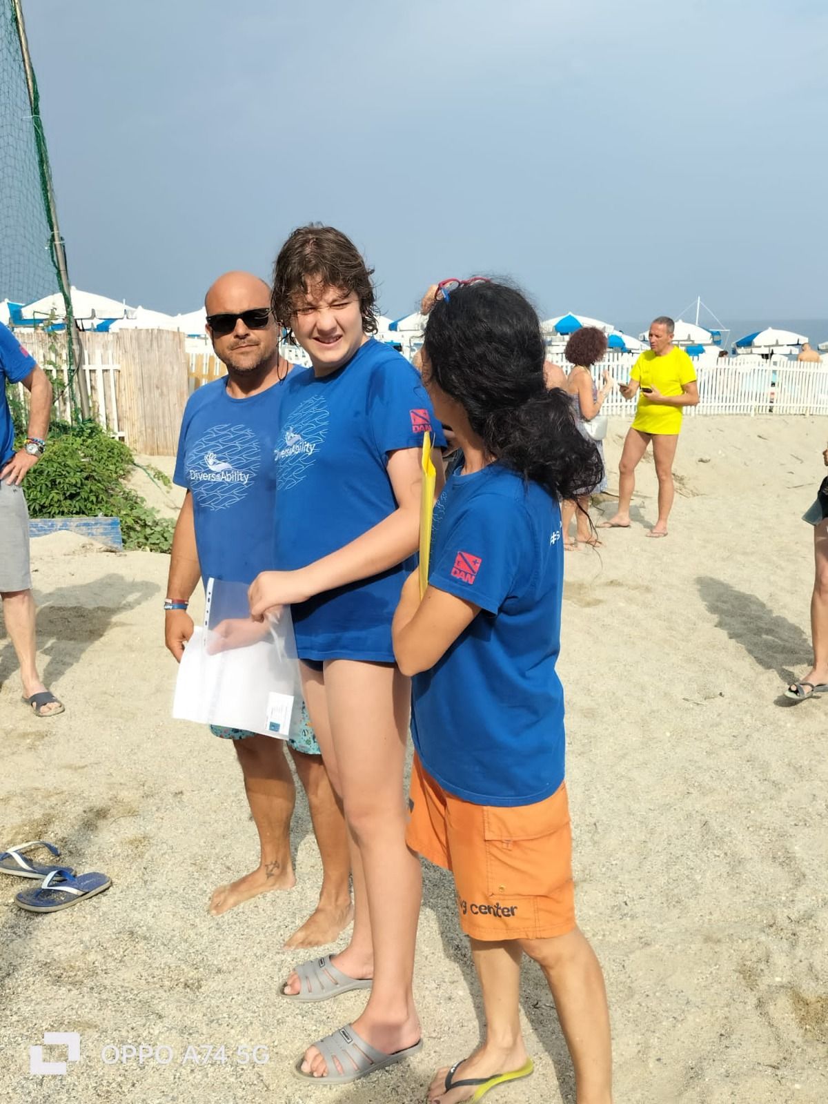 Un gruppo di persone in piedi su una spiaggia che indossano magliette blu