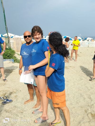 Un gruppo di persone in piedi su una spiaggia che indossano magliette blu