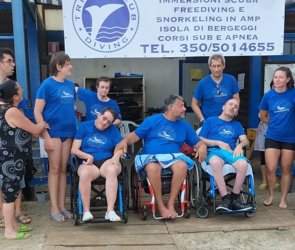 Un gruppo di persone in maglietta blu è in piedi davanti a un cartello che dice