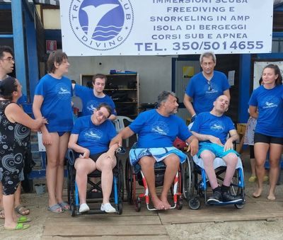 Un gruppo di persone in maglietta blu è in piedi davanti a un cartello che dice