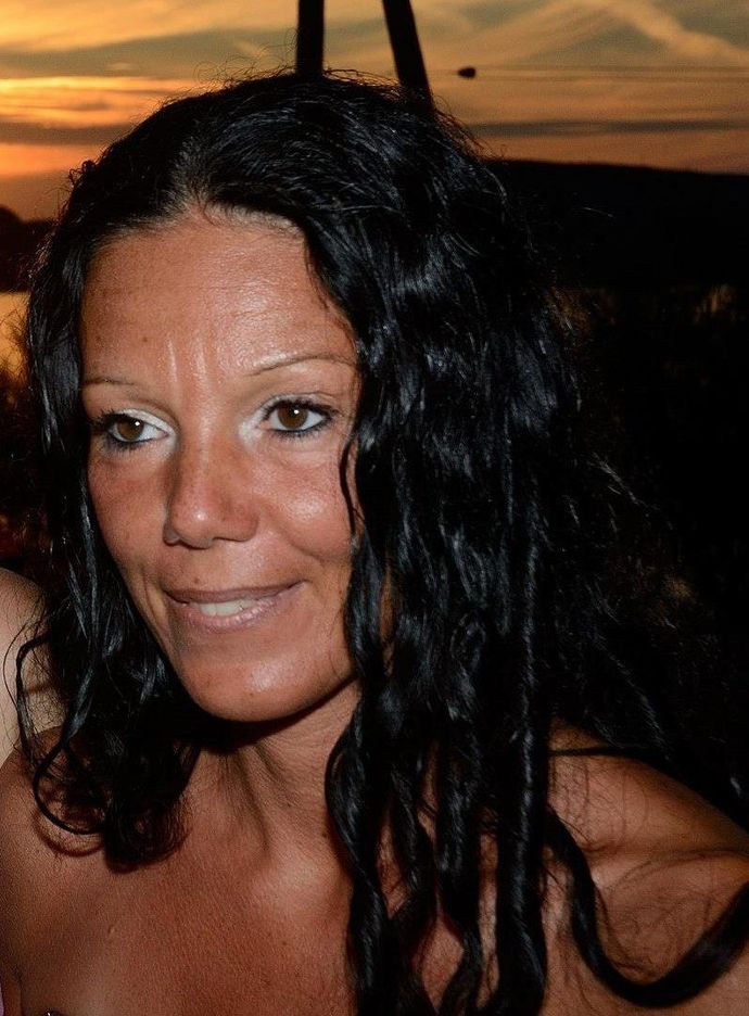 Una donna con lunghi capelli scuri sorride alla telecamera