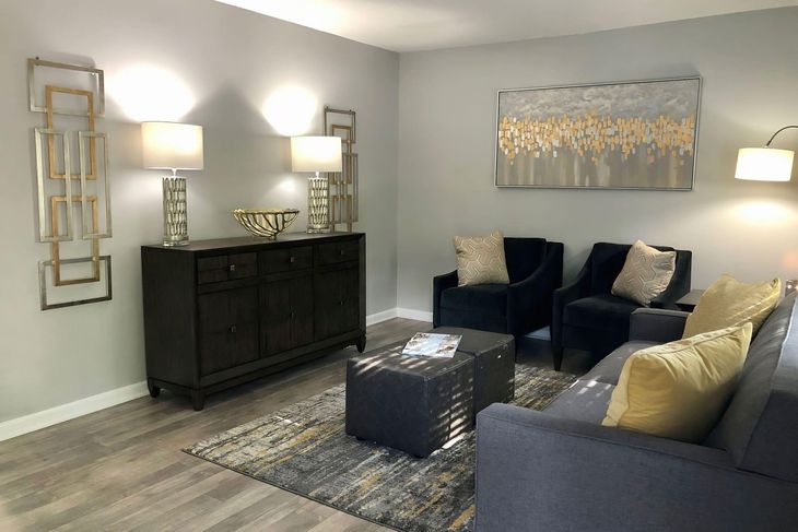 Living room with blue furniture, gold accents, gray walls and flooring.
