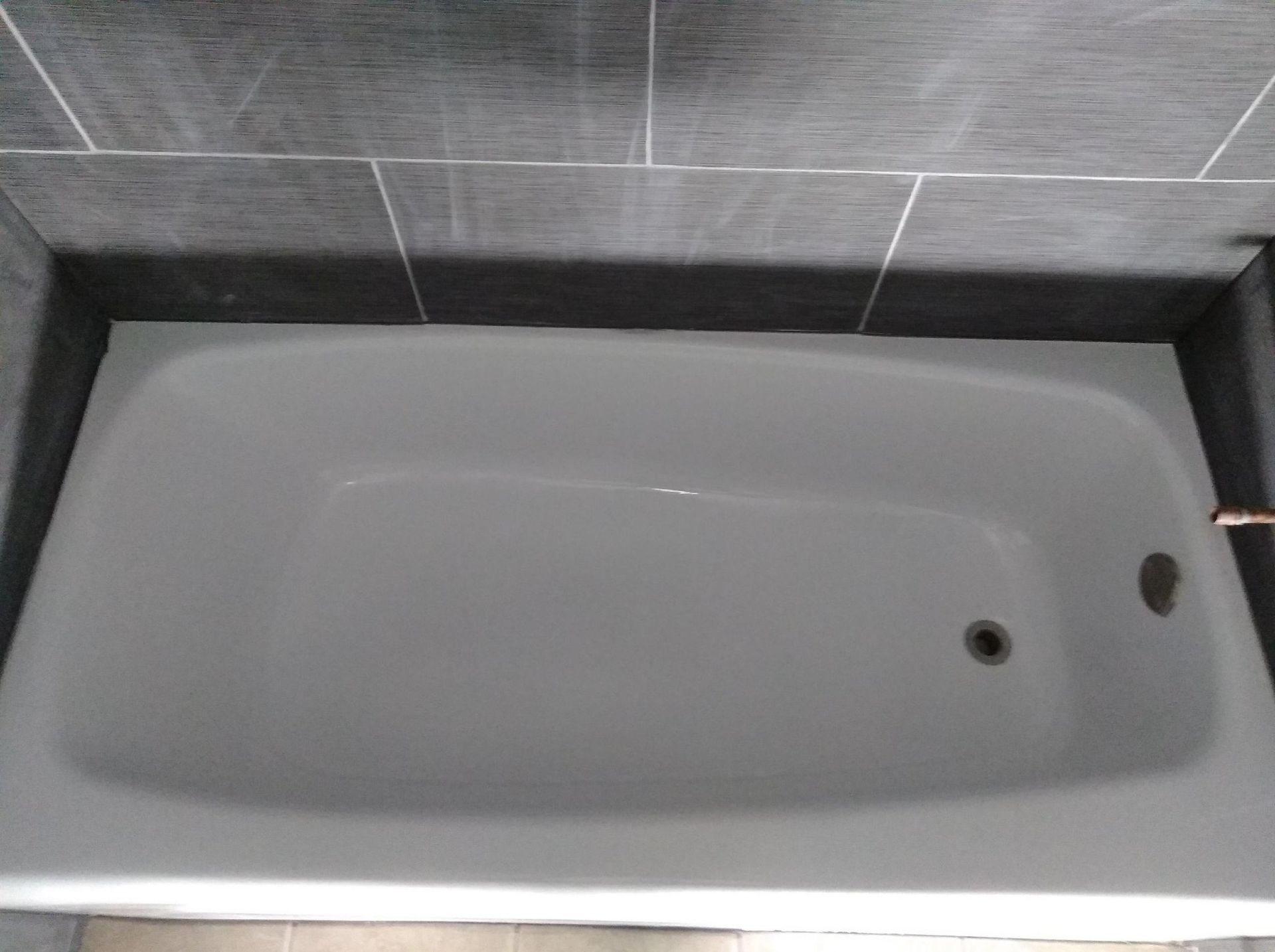 A white bathtub is sitting in a bathroom next to a tiled wall.