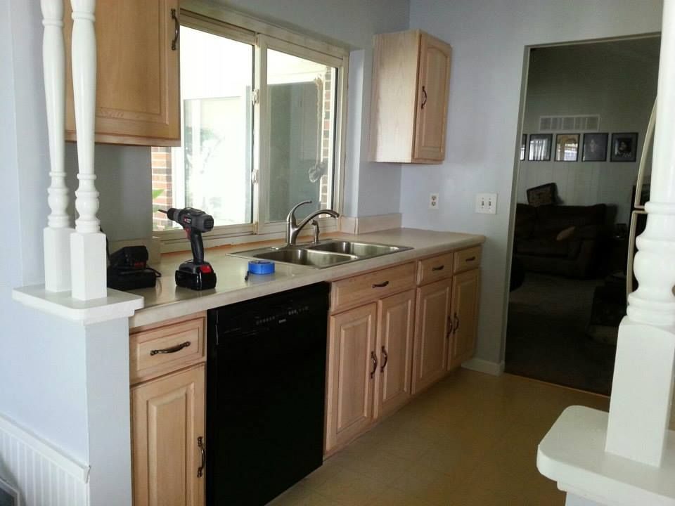A kitchen with wooden cabinets and a black dishwasher