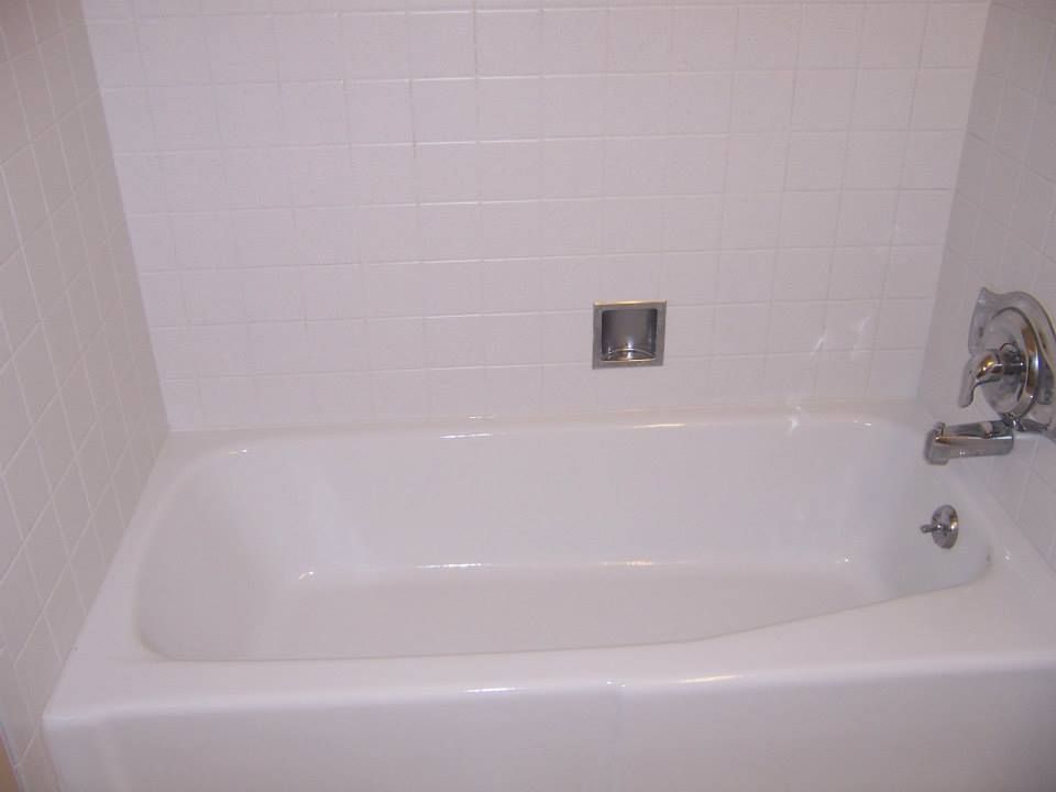 A white bathtub in a bathroom with white tile walls.