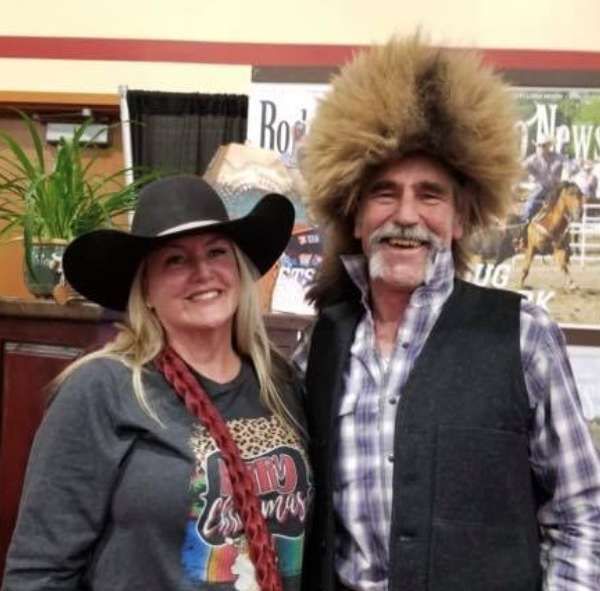 A man and a woman are posing for a picture and the man is wearing a fur hat