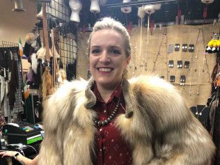 A woman is wearing a fur coat and smiling in a store.