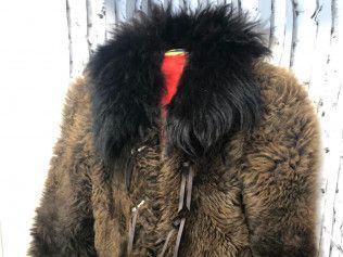 A brown fur coat with a black collar is on a mannequin.