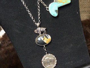 Three necklaces are sitting on a black mannequin.