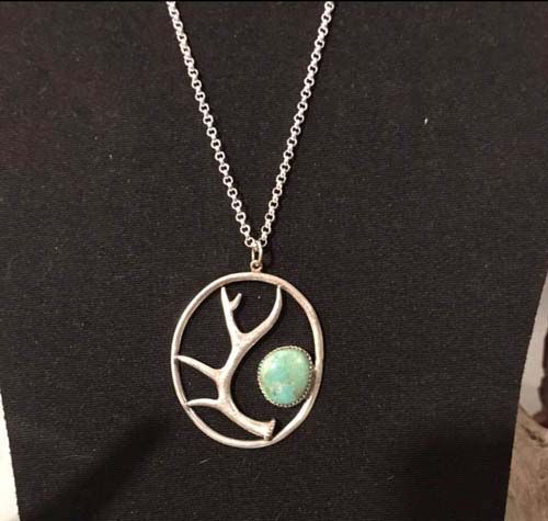 A necklace with antlers and a green stone in the center