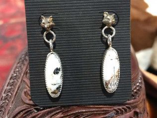 A pair of earrings are sitting on a black cardboard holder.