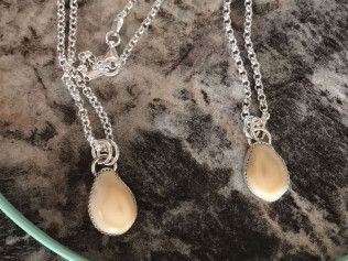 A close up of two necklaces with pendants on a chain on a table.