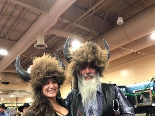 A man and a woman are posing for a picture while wearing fur hats.