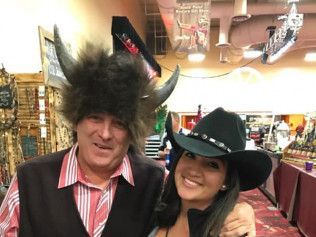 A man wearing a buffalo hat and a woman wearing a cowboy hat are posing for a picture.