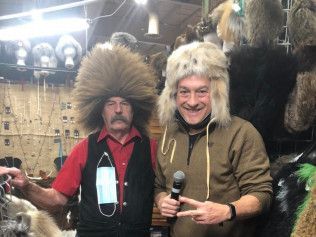 Two men wearing fur hats and a mask are standing next to each other.