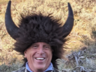 A man wearing a buffalo hat is smiling for the camera