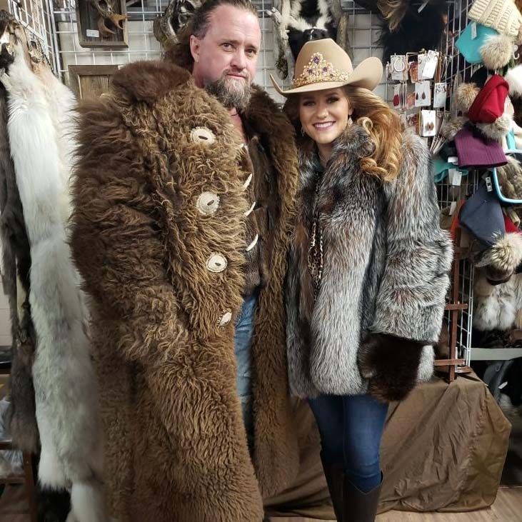 A man and a woman are posing for a picture in a fur coat.