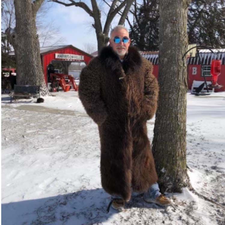 A man in a fur coat is standing in the snow