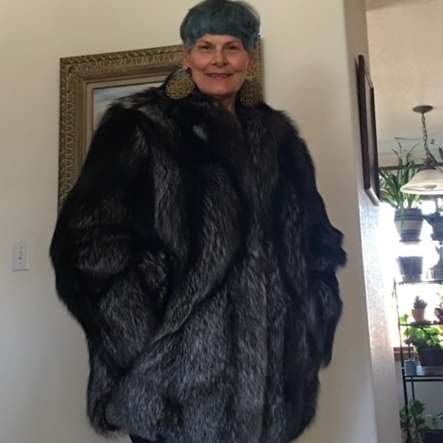 A woman is wearing a black fur coat and a blue hat.