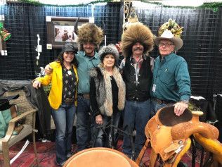 A group of people are posing for a picture in front of a saddle.
